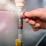 Hand adjusting a gas line connection with steam escaping, emphasizing gas leak detection and repair services by Super Plumbers in Tyler, TX.